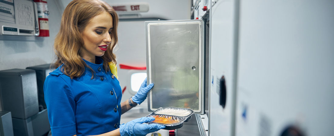 Azafata sosteniendo una bandeja de comida dentro del avión.